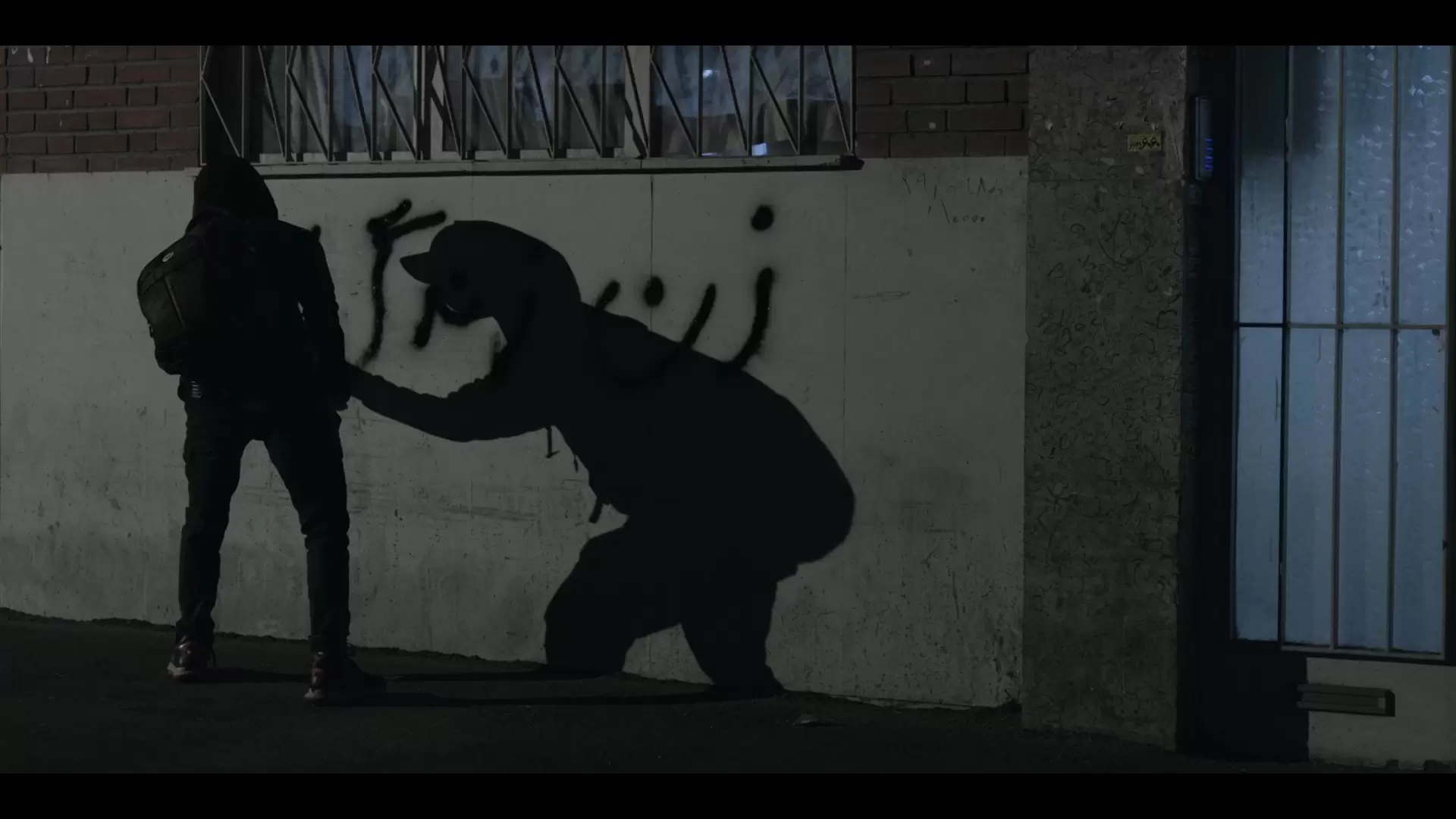 A figure beside protest graffiti at night